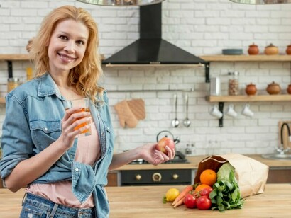 A woman in the kitchen, surrounded by fresh vegetables, preparing a meal