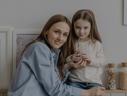 A woman and a child share a rainbow smoothie, illustrating kids making colorful smoothies together
