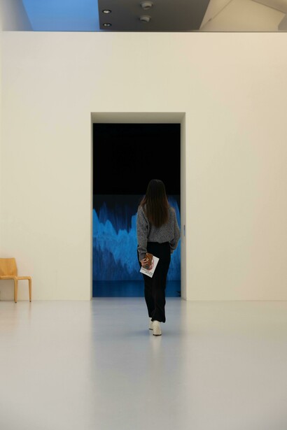 A woman walking through a modern white museum, seen from behind