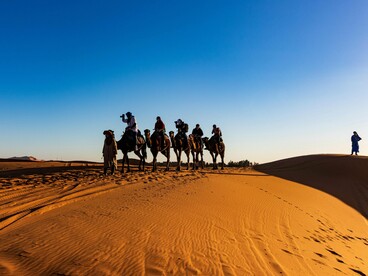 Tourists on camels progressing across a desert in Morocco, representing diplomacy built on trust, credibility, and gradual engagement