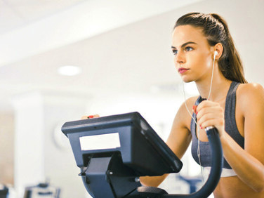 A young woman performs a HIIT cardio workout on a treadmill in a modern gym, dedicated to improving her health and endurance