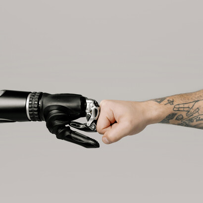 The touch between a human and robotic hand illustrates the merging of man and machine in the age of AI