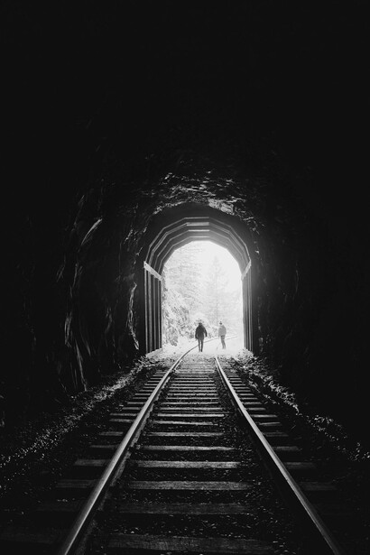 A lone silhouette in a dark tunnel approaching the light, reflecting the path toward self-discovery and true purpose