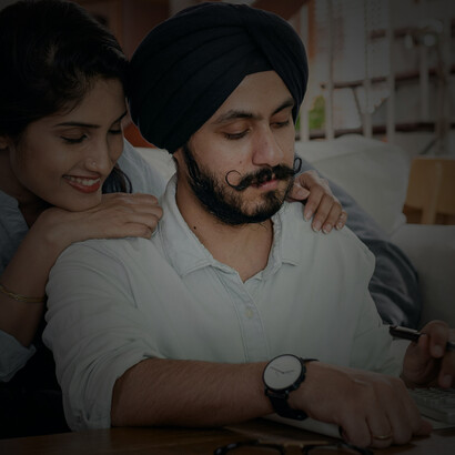 An Indian couple carefully reviewing expenses, calculating costs, and planning their household budget