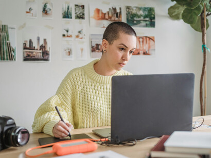 A woman combines laptop and drawing tablet in her design workflow, symbolizing digital creativity