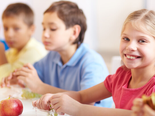 Smiling girl enjoying grapes as part of a healthy school lunch