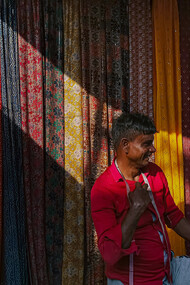 Man measuring fabrics at a market stall in India, selling textiles with care and precision