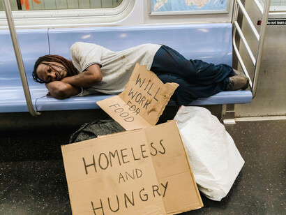 A homeless individual sleeping in the subway, reflecting the human consequences of inadequate housing policies