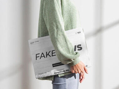 A woman holding a newspaper titled "Fake News," reflecting on the issue of misinformation