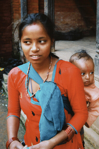 A young mother with her baby in a traditional setting, reflecting poverty and the challenges faced by girls left out of school