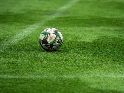 Symbole d’un jeu devenu universel, le ballon repose sur un gazon brûlé par le soleil d’été. À Barcelone, même le football semble réfléchir à son identité entre spectacle et passion populaire