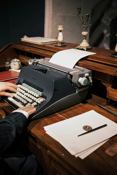 A man seated at his desk, typing intently on a typewrite