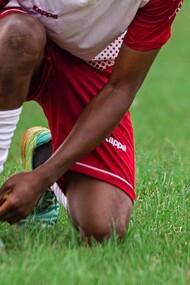 Jogador de futebol amarra a chuteira em campo