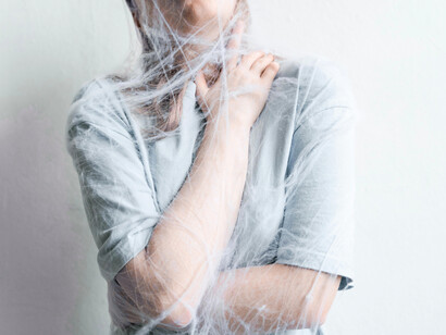 A person bound by web-like patterns, symbolizing the psyche’s vulnerability to suggestion and myth-making