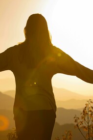 Una persona che apre le braccia al tramonto come forma di meditazione e gratitudine