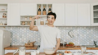 A man holds a whisk over a bowl of pancake mix, working as a chef