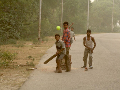 Indian children playing a lively game of cricket on a neighborhood street