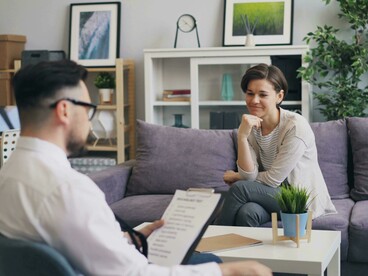 A man and a woman sit together on a couch, engaged in conversation