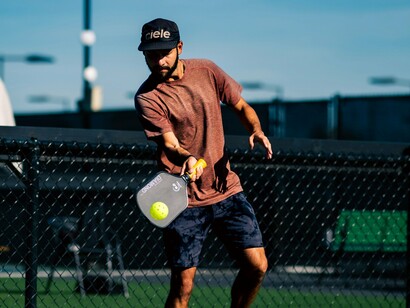 A focused player in a brown shirt and dark shorts skillfully returns a shot, showcasing the agility needed for quick direction changes