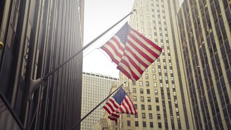 Bandiere americane che sventolano tra i grattacieli di una città finanziaria negli Stati Uniti