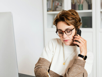 A professional balancing digital work and a phone call at her desk, highlighting the impact of distractions on meaningful communication