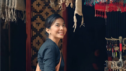 A woman standing in a fabric store, mirroring the Baduy’s devotion to handwoven textiles as carriers of ancestral meaning