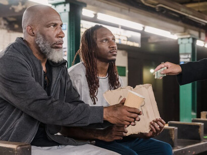 In the heart of New York City, two men ask for help—a quiet reminder of those often overlooked