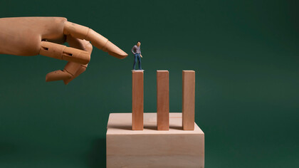 One individual is seen attempting to make the dominoes fall, symbolizing the pressure placed on employees to meet unrealistic expectations 