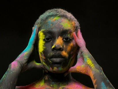 Model posing with colorful powder, gently touching his head—silent communication and mind meditation captured in a thoughtful person with eyes closed