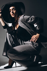 A woman in a business suit, accessorized with a hat