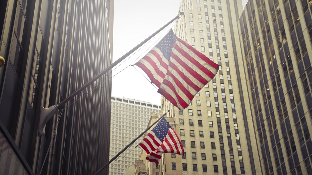 Bandiere americane che sventolano tra i grattacieli di una città finanziaria negli Stati Uniti
