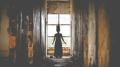 A woman standing behind the ruins of a torn-down castle, creating a spooky thriller atmosphere