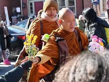 Un monaco buddista prende dei fiori dalla mano di uno spettatore lungo la strada durante la Marcia per la Pace. Foto di G. Edward Johnson