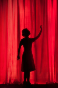 A silhouette of three performers on stage, captured in mid-action, highlights the energy and creativity of an improv performance
