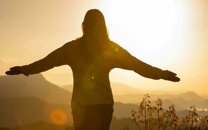 Una persona che apre le braccia al tramonto come forma di meditazione e gratitudine