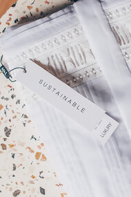 Sustainable fashion, sunglasses sitting on folded white shirt, on top of terrazzo side table