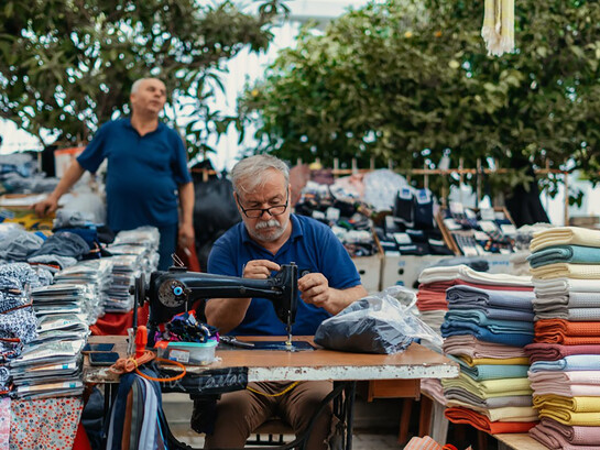 A man sitting at a table, with a gun beside him and a pile of laundry nearby, Turkey