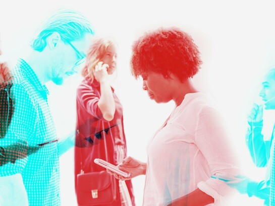 Individuals seemingly engrossed in their smartphones, representing pervasive connectivity and a culture of individuation in the evolving network society