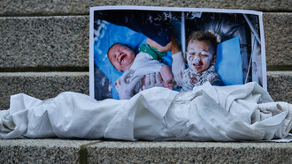 Image of two deceased children in Gaza, wrapped in shrouds, displayed during protests