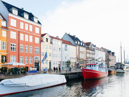 Colorful boats line the waterways, with historic city buildings adding charm to the picturesque landscape of Copenhagen, Denmark