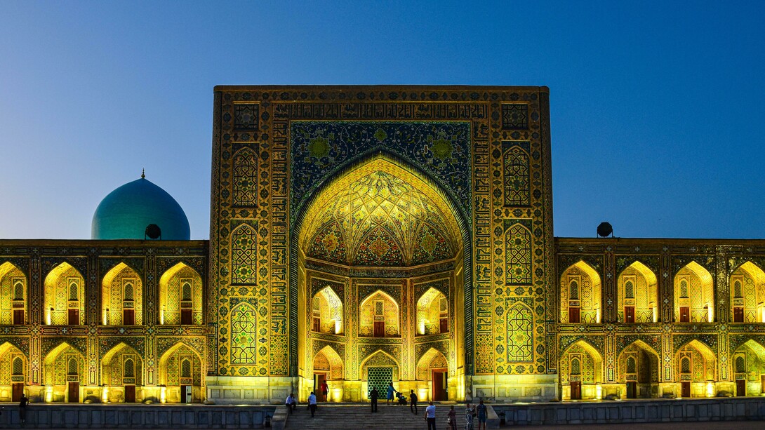 Night view of the Tilya Kori Madrasah in Samarkand, Uzbekistan, famed for its golden interiors and role as both a mosque and madrasa