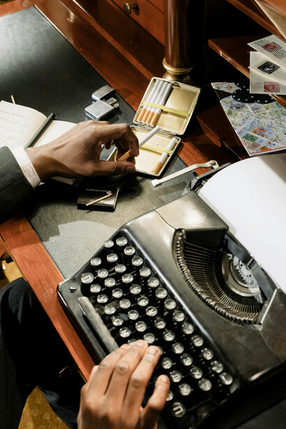 A man typing on a typewriter at his desk