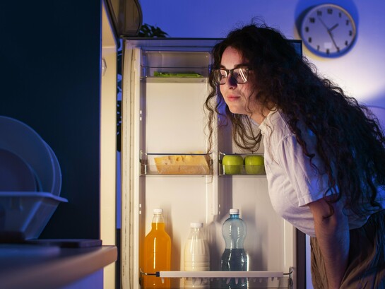 A woman studying her fridge, symbolizing the need to look deeper than dates and cool air