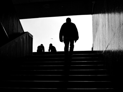 A black and white photo of men’s silhouettes on subway steps, evoking loneliness