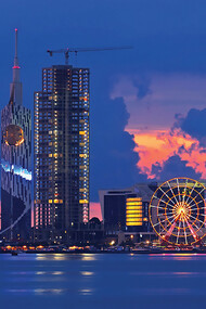 As the sun sets over Batumi, Georgia, the cityscape transforms into a mesmerizing tapestry of warm hues, casting a spellbinding glow over the charming coastal city