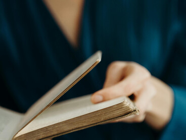 Close-up of hands holding an open book, representing the depth of wisdom and accumulated experience