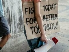 A woman carrying a banner urging to take action now to create a better future