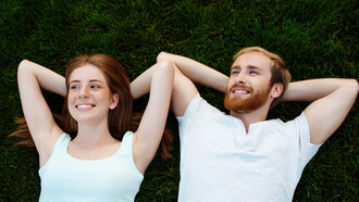 Una coppia felice, un uomo e una donna, giacciono sull'erba sorridendo