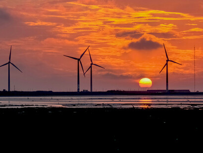 Wind turbines at sunset, symbolising the promise and challenges of renewable energy