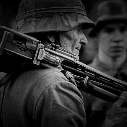 Grayscale photo of an elderly man holding a rifle